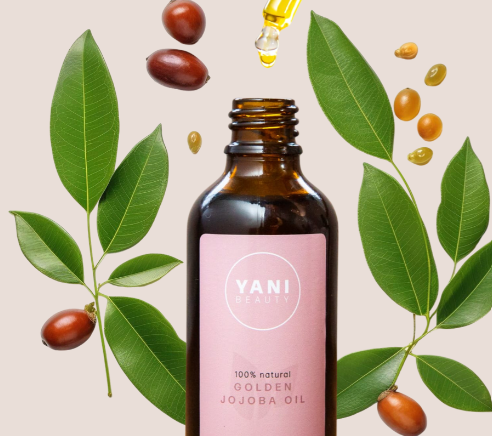 Yani Beauty golden jojoba oil bottle surrounded by jojoba leaves and nuts